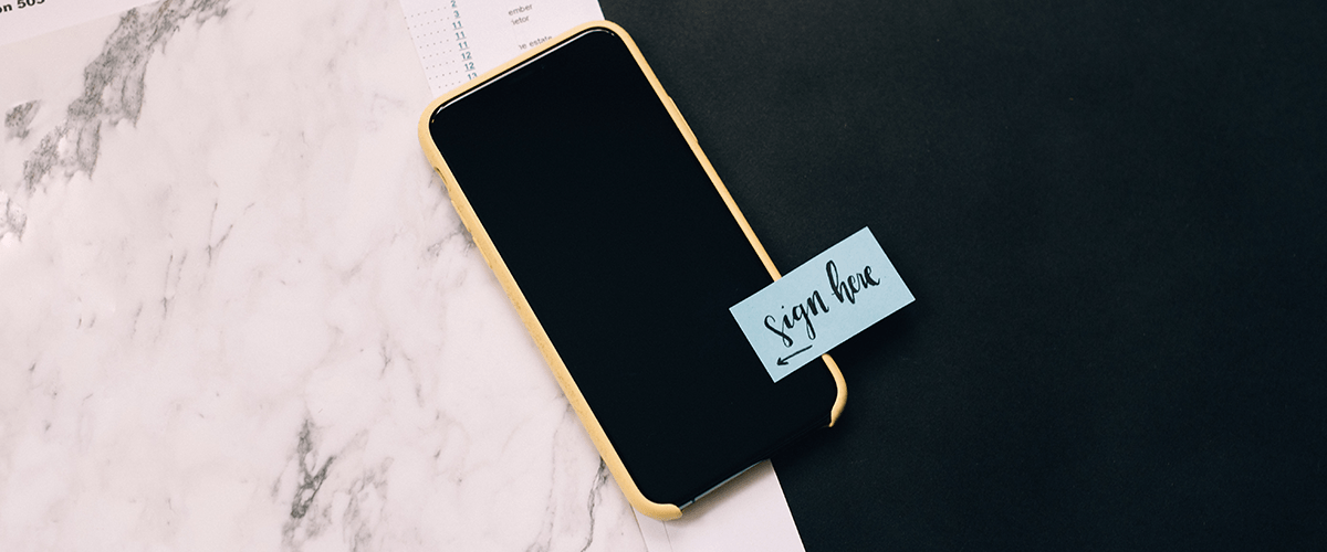 Folder, phone and note that reads "sign here." Photo by Kelly Sikkema on Unsplash