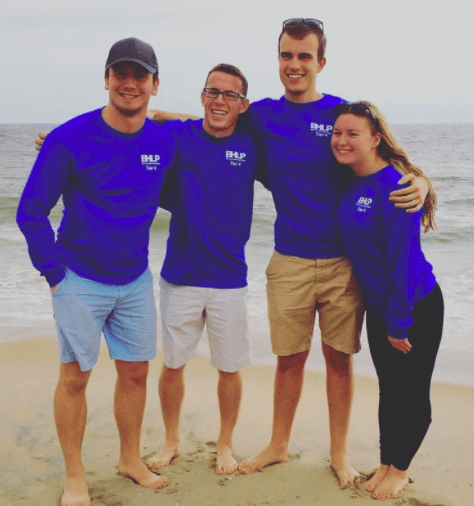 Four students wearing matching blue BHLP shirts and are standing by the ocean