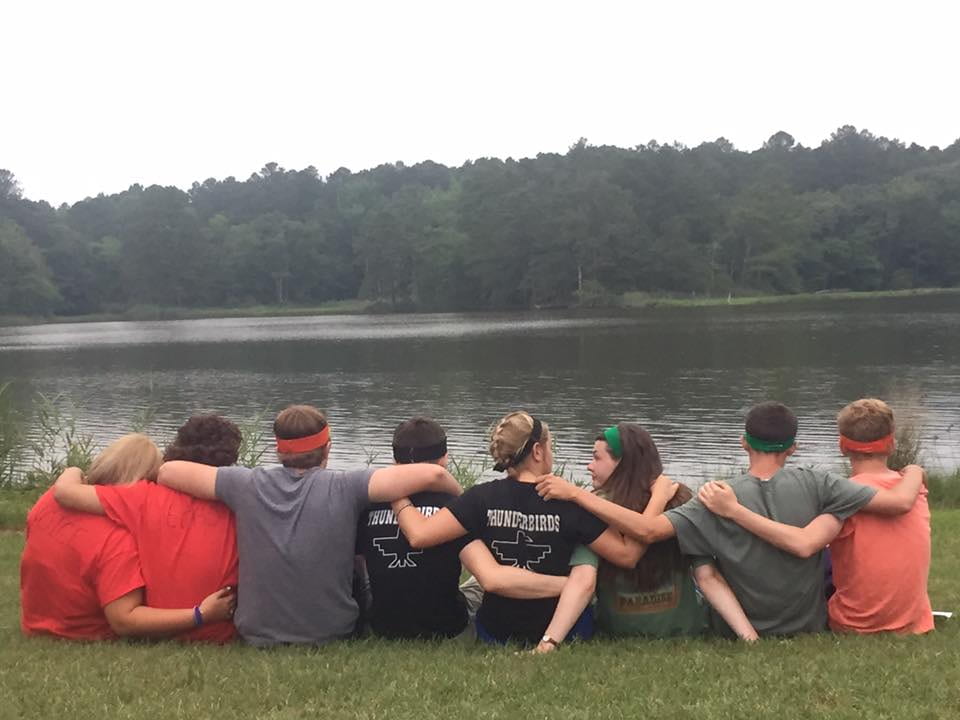 Friends sitting arm in arm, looking at lake