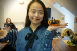 Linhan "Angelina" Xu holds up her decorated mini pumpkin in Monica Farling's third-floor classroom at the ELI's building at 189 West Main Street.