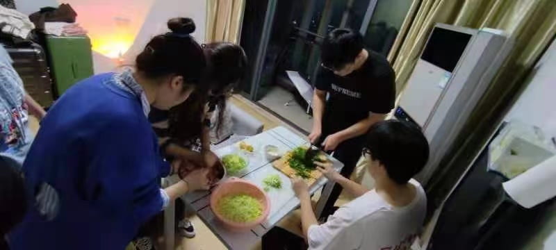 UD-IC students gather around a table to make dumplings