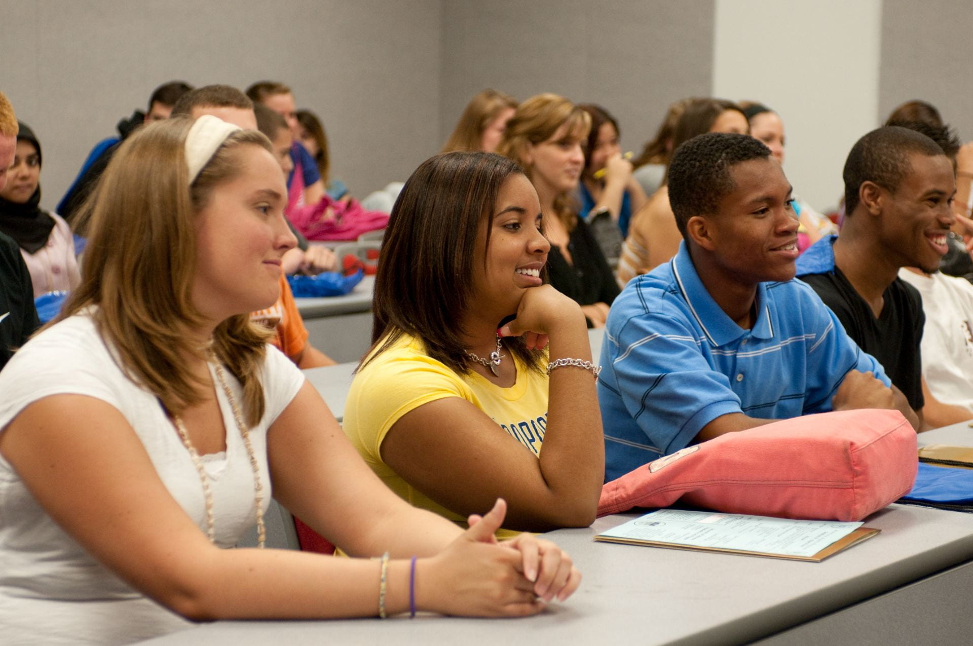 A front angled view of students seated in a classroom paying attention to a lecture.