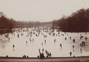 Early twentieth-century photograph showing hundreds of individuals skating on an outdoor pond.