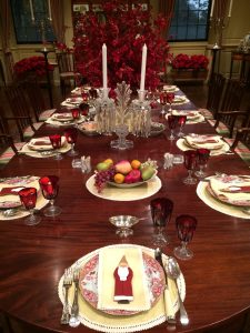 During Winterthur's Yuletide 2017 tour, the du Pont Dining Room table is set with red patterned ceramics and glassware, with a traditional-looking St. Nicholas cookie on the center of each dish, completing the festive atmosphere. 