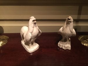 A photograph of two ceramic roosters.  One is the same as the one the previous figure, the other is made out of salt-glazed stoneware.