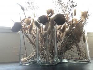 a glass biomorphic vase with dried flowers in it