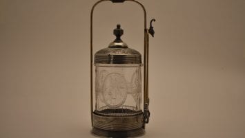 Pressed glass jar with engraved metal lid, stand, and tongs with talon grabbers and an eagle’s head hook.