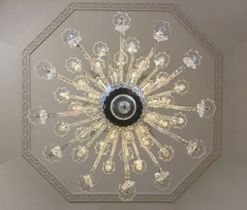 Another star-like pattern of a chandelier from below. The octagon molding on the ceiling can be seen behind it.