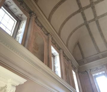 A corner of a room with Neoclassical decorative elements. The limestone of the columns and niches is a salmon-pink.