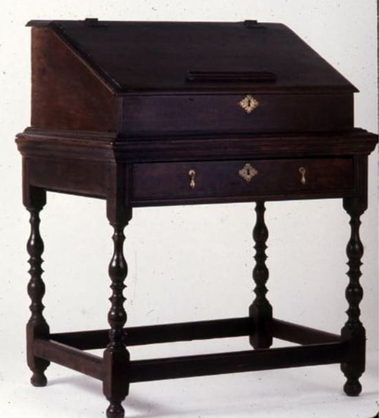 Alt Text: A slant-front desk box with its lid closed on a frame with four turned legs and rectilinear stretchers.