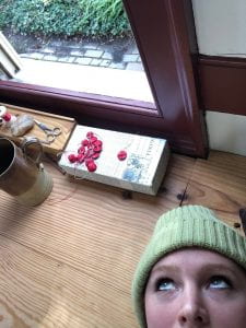 The author takes a selfie while she is laying on a tailor’s platform in front of an open window.