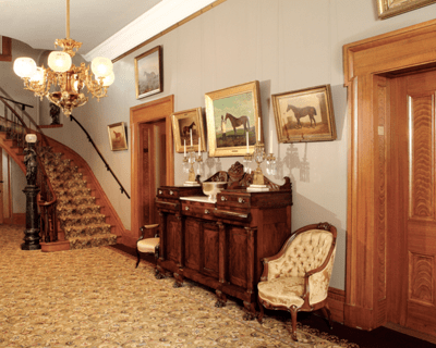 Figure 1. Entrance hall with stand, chairs, staircase, and paintings of horses on the wall. 