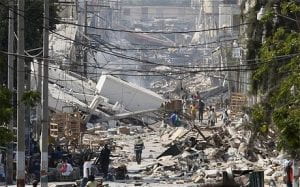 2010 earthquake wreckage ("People walk on a debris-covered street")