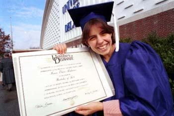 A graduate of the class of 1995 displays her new diploma in front of the Delaware Field House.