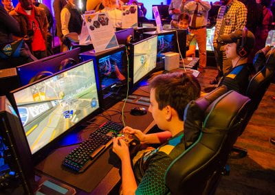 Students play at video game stations as guests look on