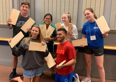 QUEST Students holding wooden boards that they broke in half