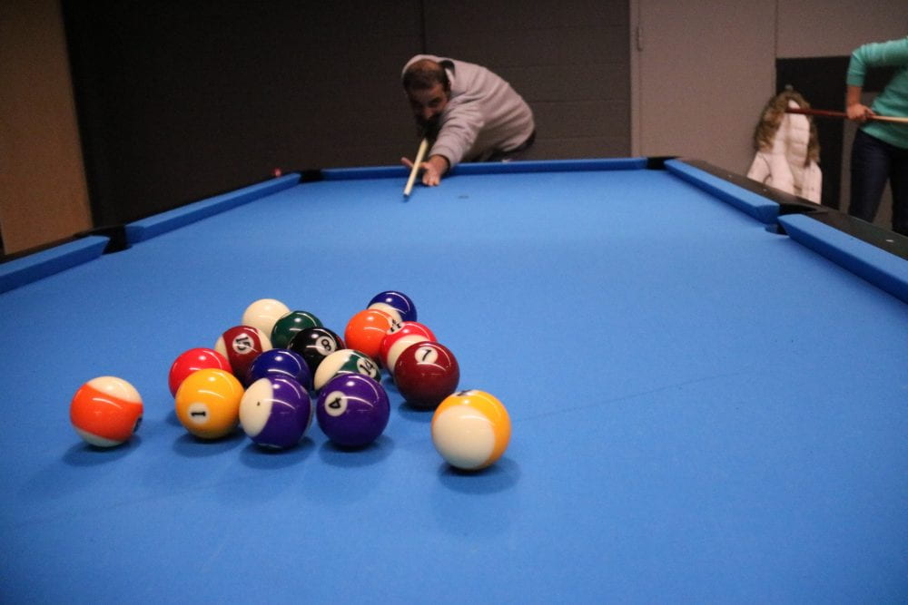student shooting pool in Hen Zone