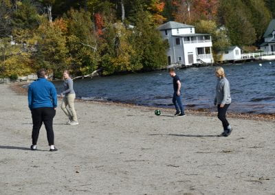 Group members playing soccer on the beach
